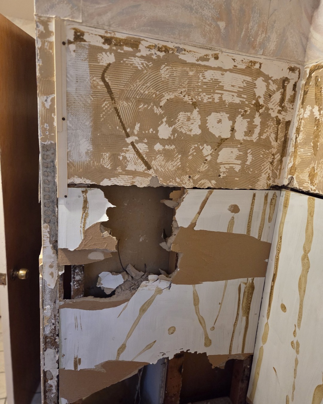 Bathroom before remodel with torn-out wall tile, damaged drywall and exposed framing