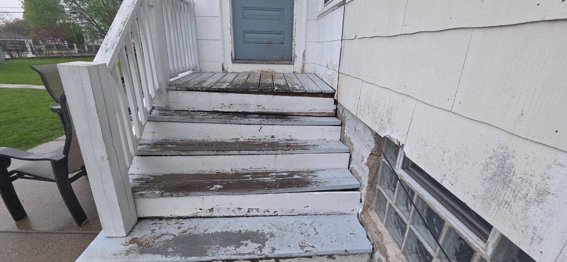 Weathered wooden porch stairs and railing with heavy peeling paint before restoration